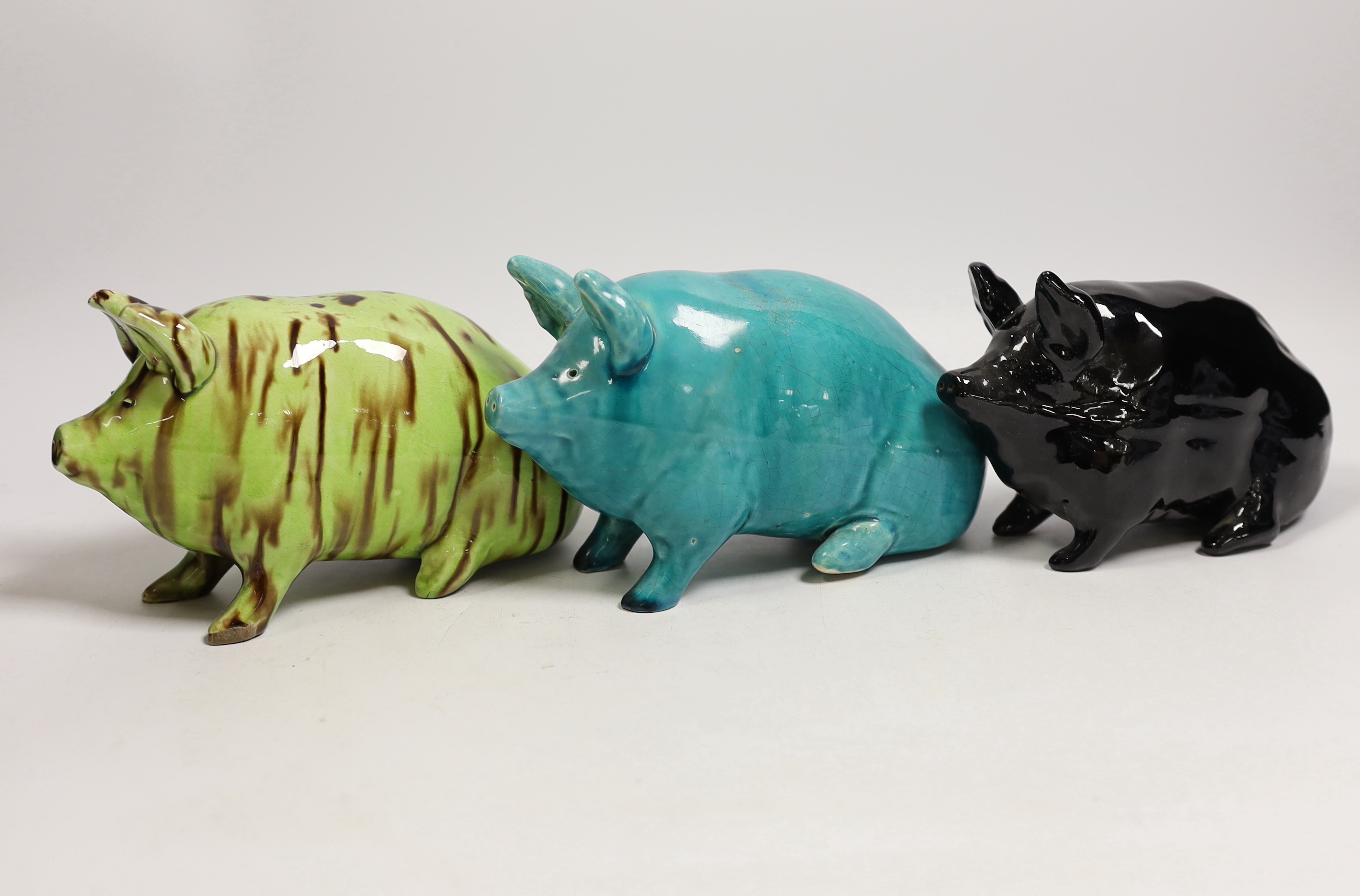 Three Wemyss style pigs in turquoise, pale green / brown and black glazes, one indistinctly marked W.. 15cm